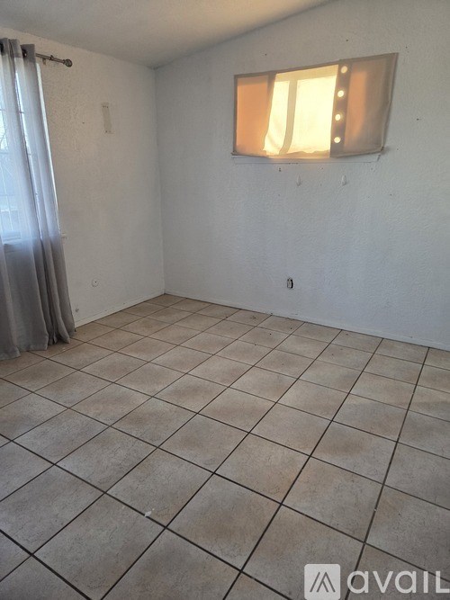 A room with a tiled floor and a window with blinds.