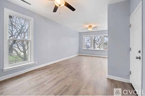 A room with a ceiling fan and a window showing a tree outside.