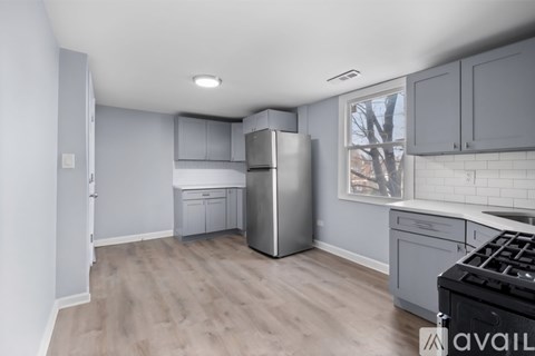 A kitchen with a stainless steel refrigerator and wooden flooring.