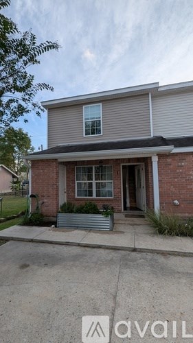 A house with a grey roof and a brick wall is available for rent.