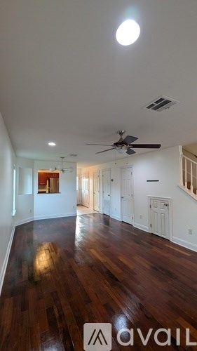 A room with a ceiling fan and wooden floors.