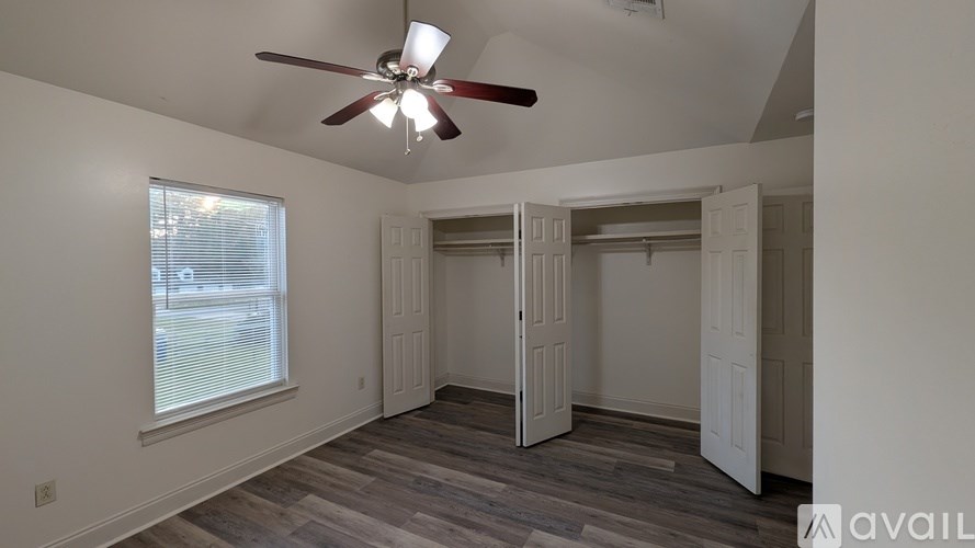 A room with a ceiling fan and a window with blinds.
