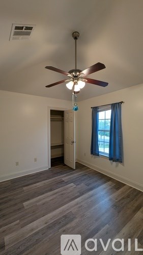 A room with a ceiling fan and a window with blue curtains.