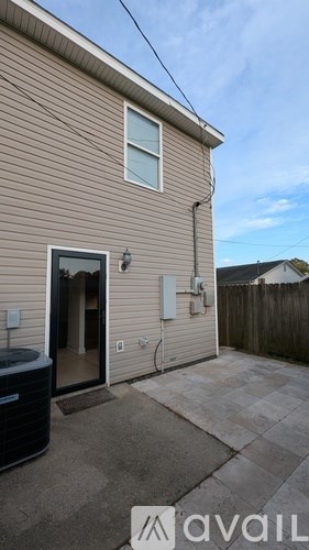 A house with a beige siding and a black trash bin in front of it.