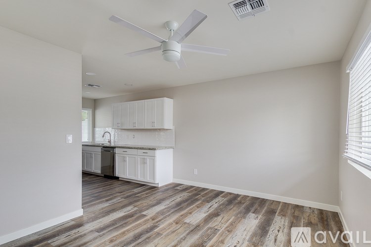 A room with a ceiling fan and wooden flooring.
