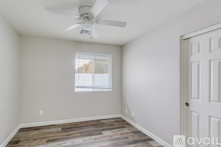A room with a ceiling fan and a window with blinds.