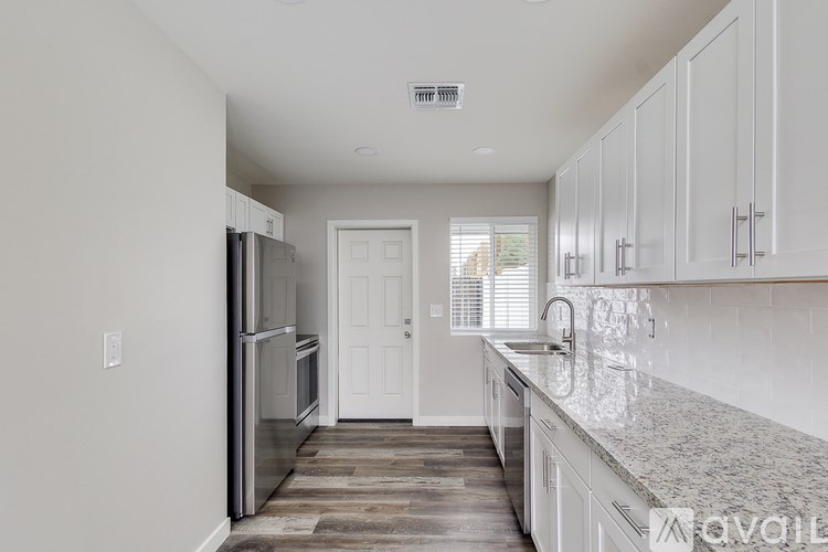 A kitchen with white cabinets and a granite countertop.