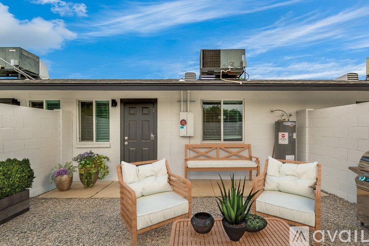 A patio with a table, two chairs, and a potted plant.