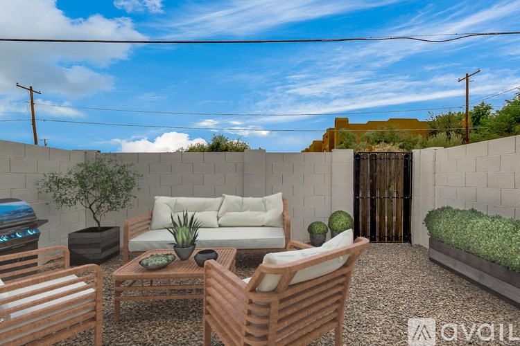 A patio with a sofa, chairs, and a table with a potted plant on it.