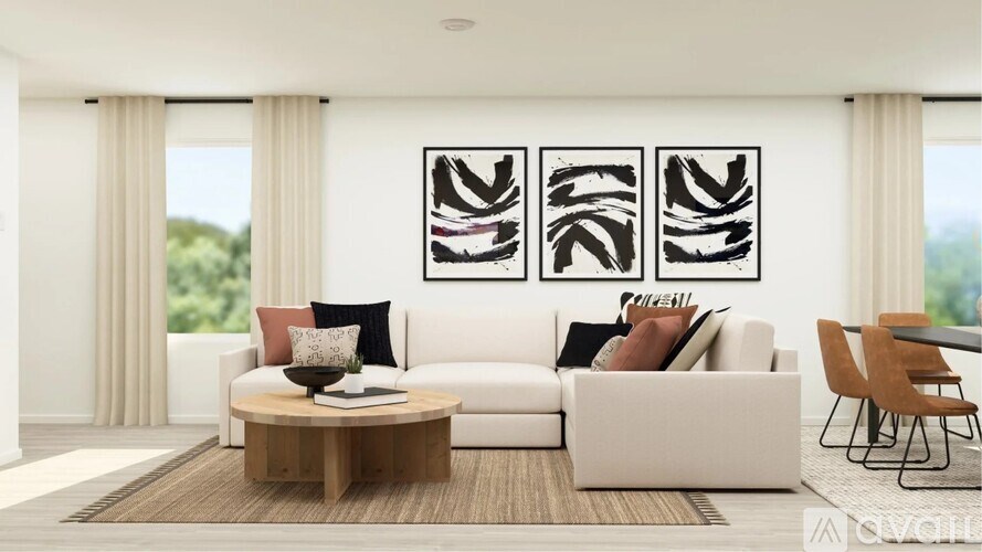 A modern living room with a white sofa, a coffee table, and a large abstract painting on the wall.