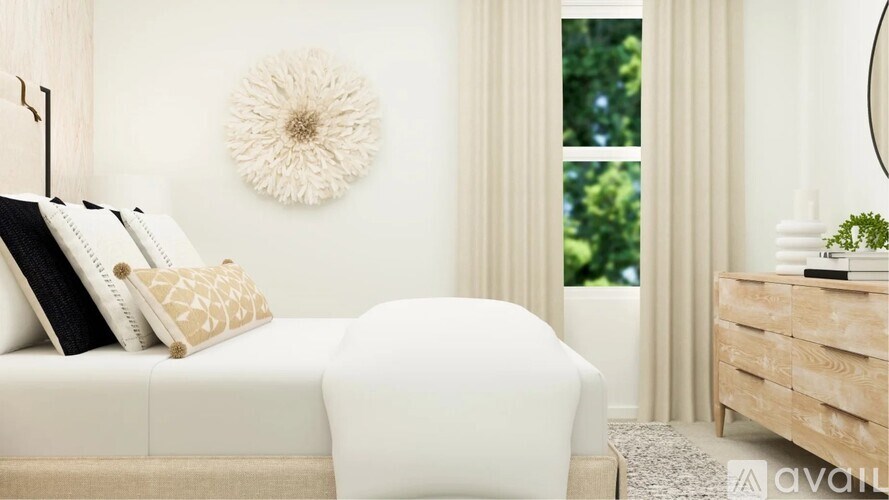 A white bedroom with a large bed, a round decorative item on the wall, and a wooden nightstand.