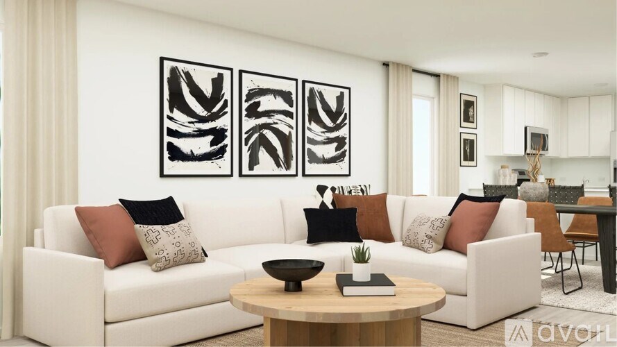 A modern living room with a white sofa, a wooden coffee table, and three abstract black and white paintings on the wall.