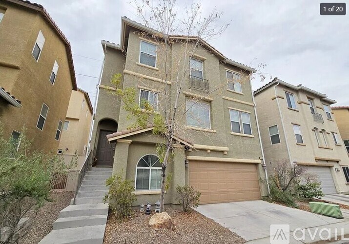A beige two-story house with a garage and a tree in front.