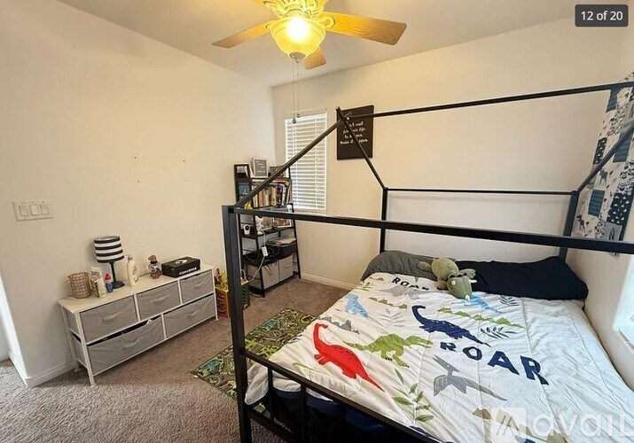 A bedroom with a bed, a dresser, and a ceiling fan.