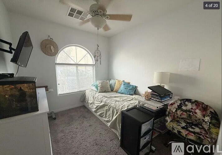 A bedroom with a bed, a ceiling fan, and a window with blinds.