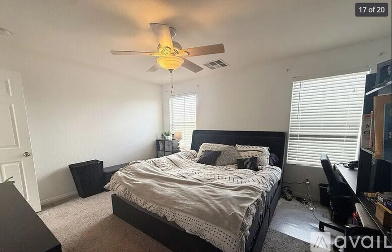 A bedroom with a bed, a ceiling fan, and a window with blinds.