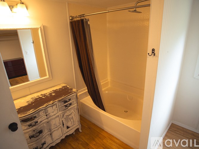 A bathroom with a white tub and a brown and white dresser.