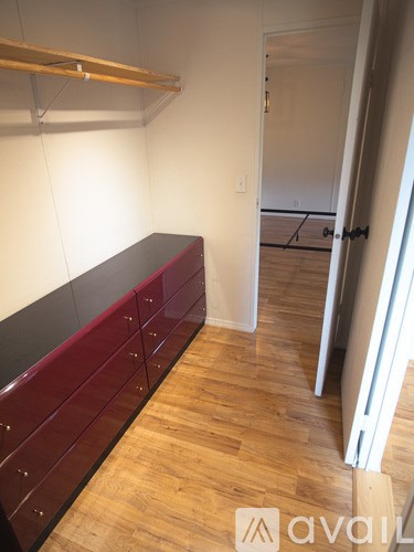 A room with a long red bench and wooden floors.