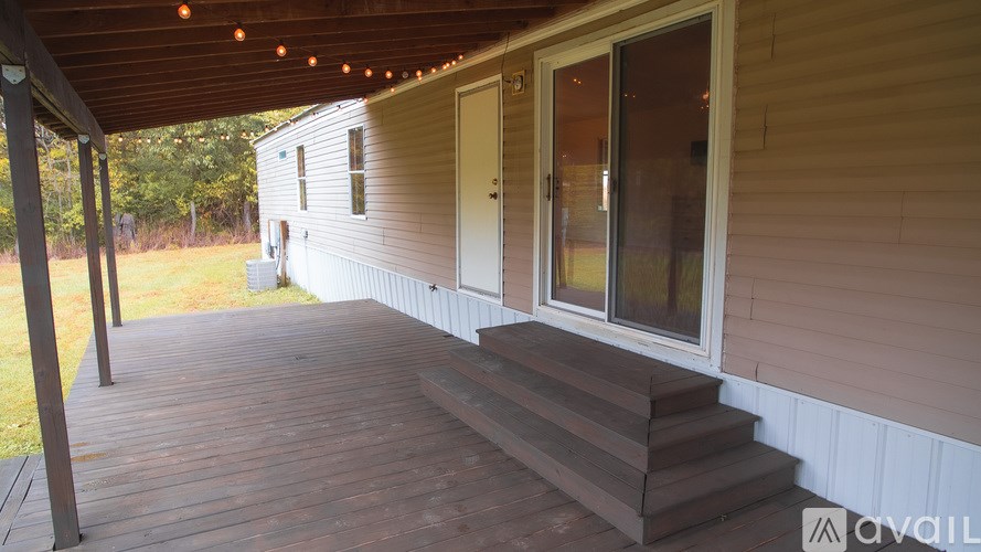 A wooden deck with steps leading to a door and windows.