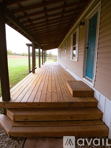 A wooden porch with a blue door and steps leading to it.