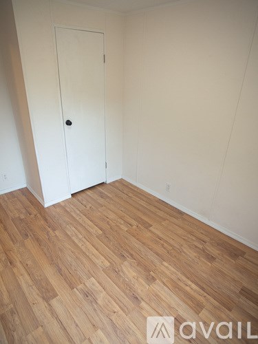 A room with a white door and wooden flooring.