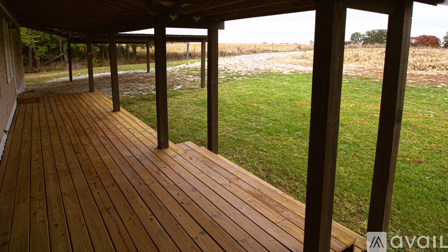 A wooden deck with a view of a grassy field.