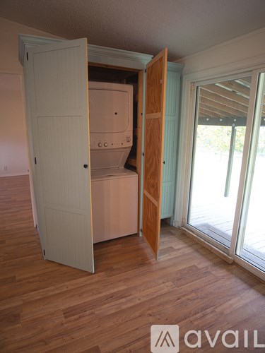 A white door is open to a room with wooden floors.