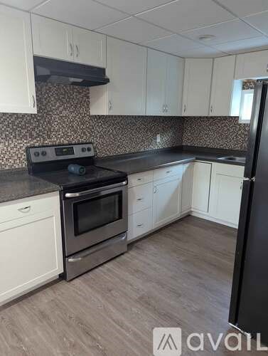 A kitchen with white cabinets and a black refrigerator.