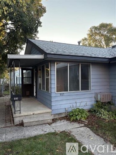A small house with a porch and a mailbox on the front door.
