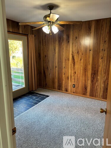 A room with wooden walls and a ceiling fan.