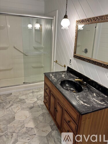 A bathroom with a marble countertop and a walk-in shower.