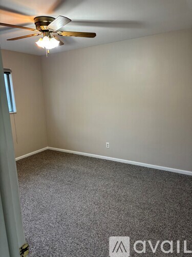 A room with a ceiling fan and carpeted floor.