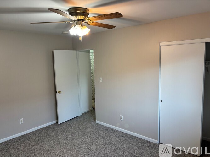 A room with a ceiling fan and a white door.