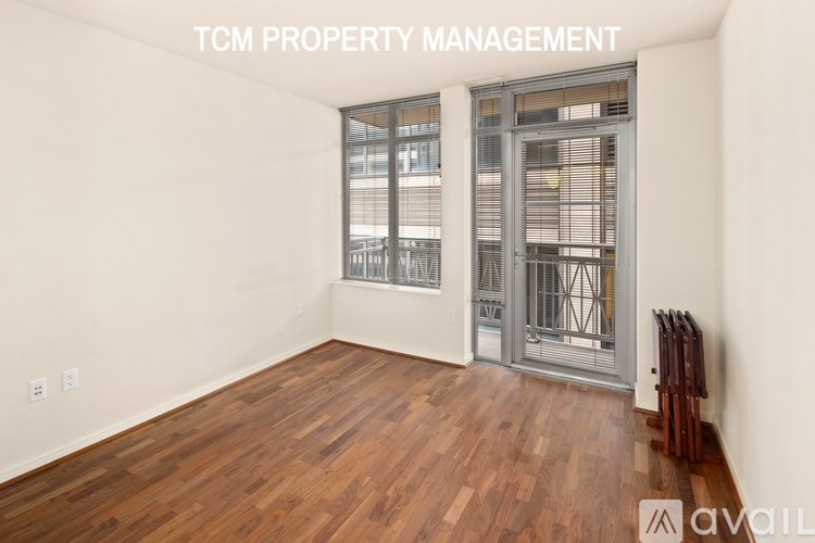 A room with wooden flooring and a glass door leading to a balcony.