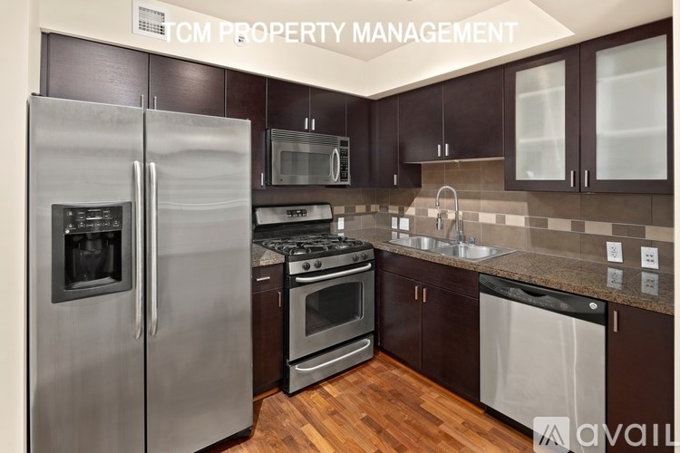 A kitchen with a stainless steel refrigerator and wooden floors.
