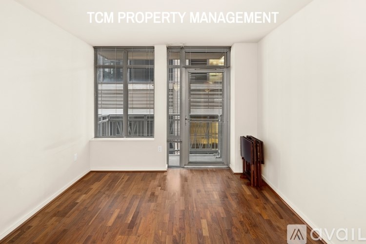 A room with wooden floors and a glass door leading to a balcony.