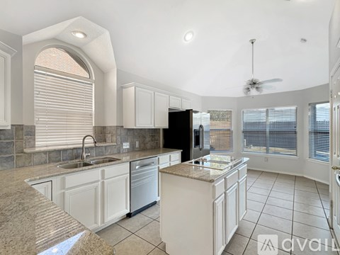 A kitchen with a black refrigerator and white cabinets.