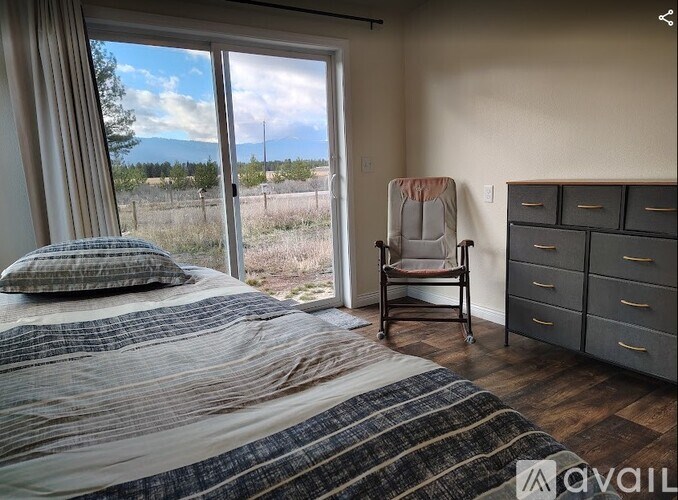A grey house with a window and a chair outside.