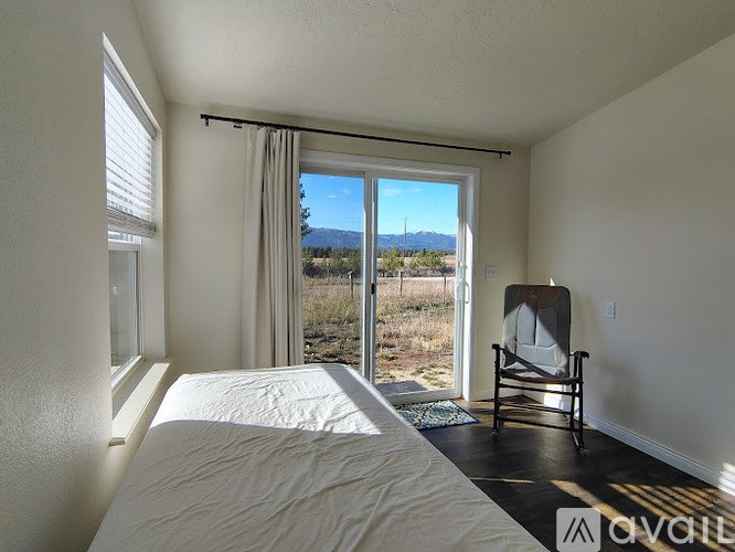 A bedroom with a large bed and a chair by the window.
