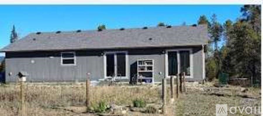 A grey house with a brown door and windows.