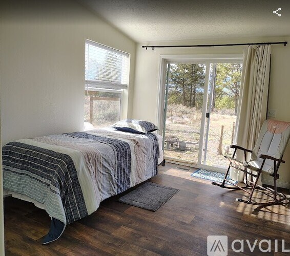 A bedroom with a bed, chair, and sliding glass doors.