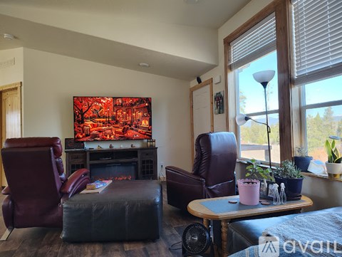 A living room with a red chair and a fireplace.
