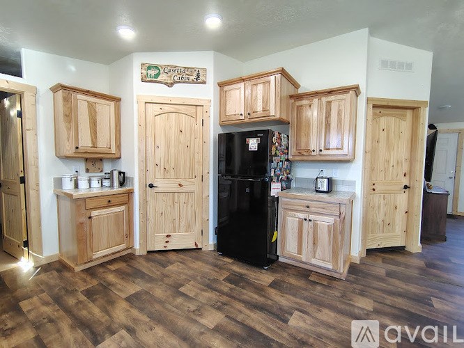 A kitchen with wooden cabinets and a black fridge.