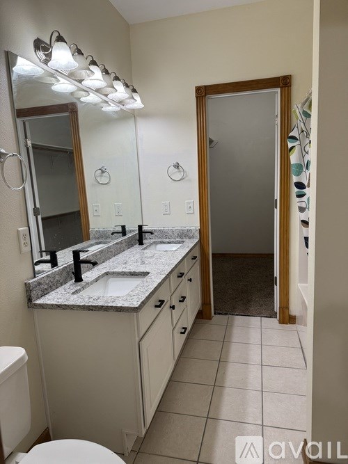 A bathroom with a toilet, sink, mirror, and a shower.