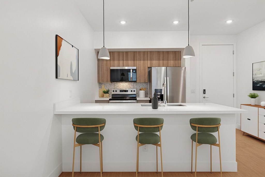 A modern kitchen with a white countertop and green chairs.