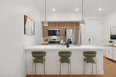 A modern kitchen with a white countertop and green chairs.