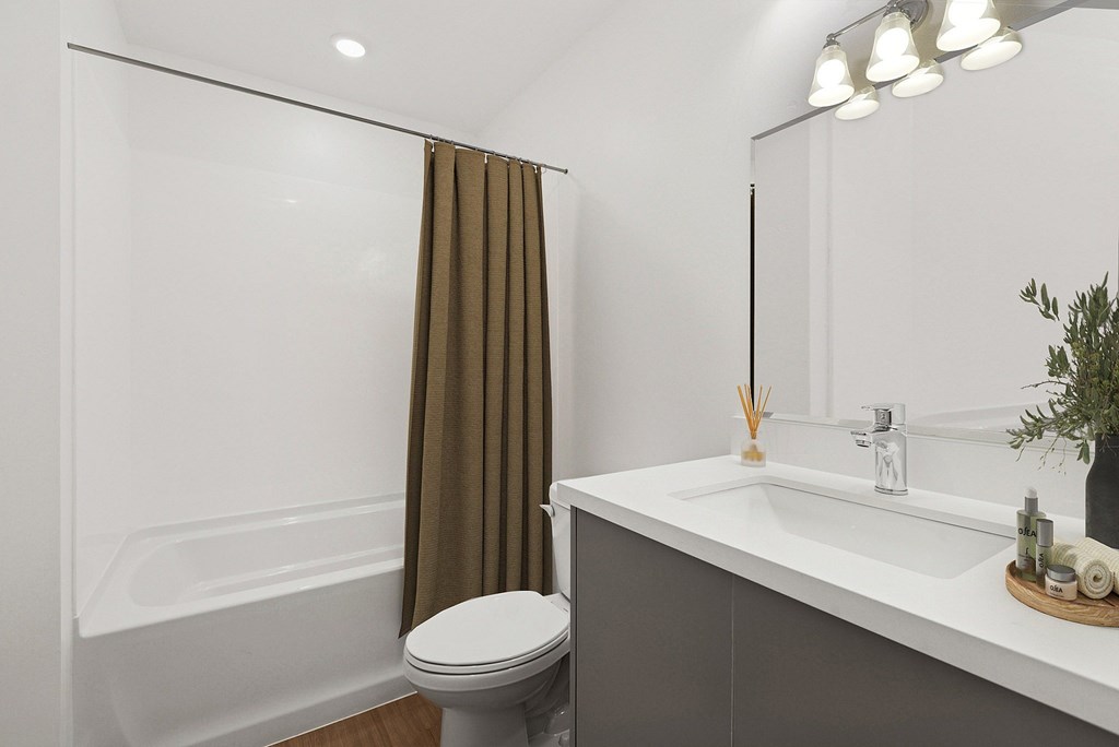 A white bathroom with a toilet, sink, and shower.