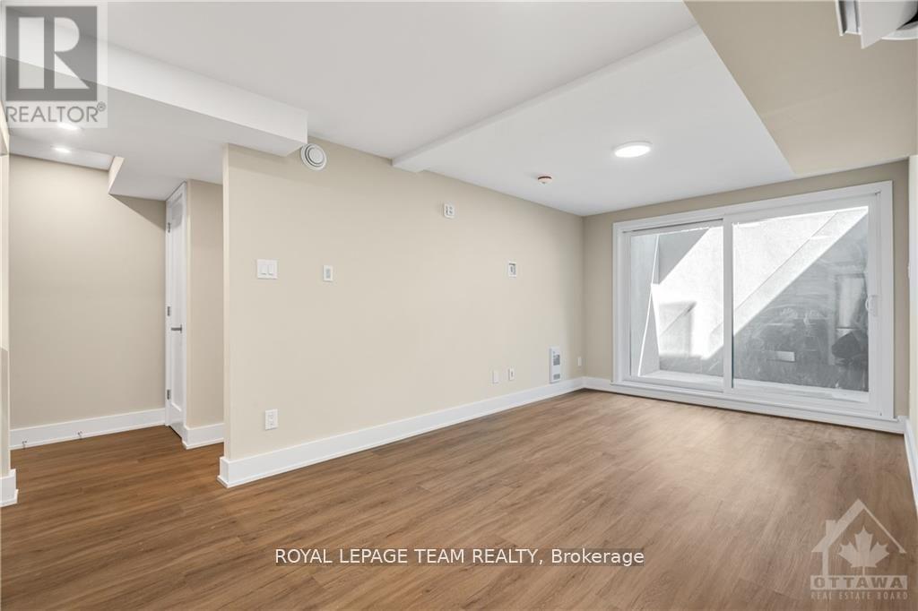 A spacious room with wooden flooring and a large window.