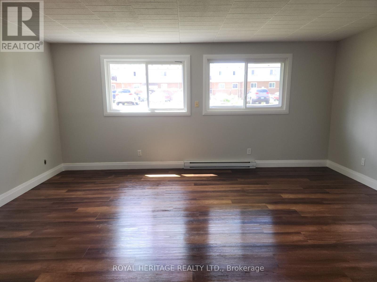 A room with wooden floors and two windows.
