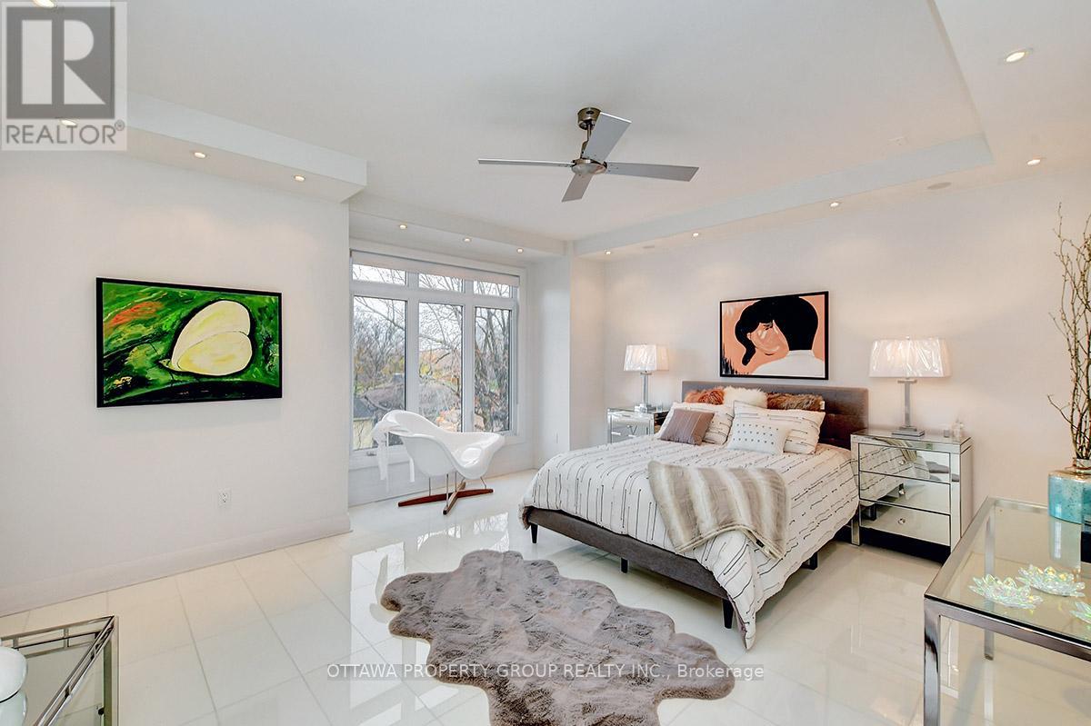 A bedroom with a bed, a painting, and a glass table.